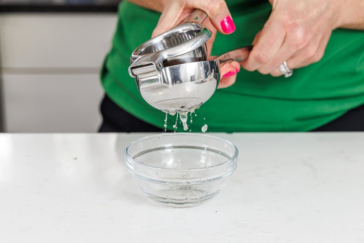 Juicing a lemon into a small glass bowl.