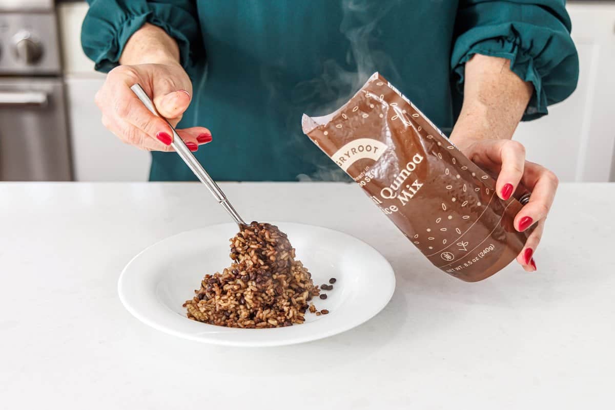 Adding rice and quinoa mix to a white bowl.