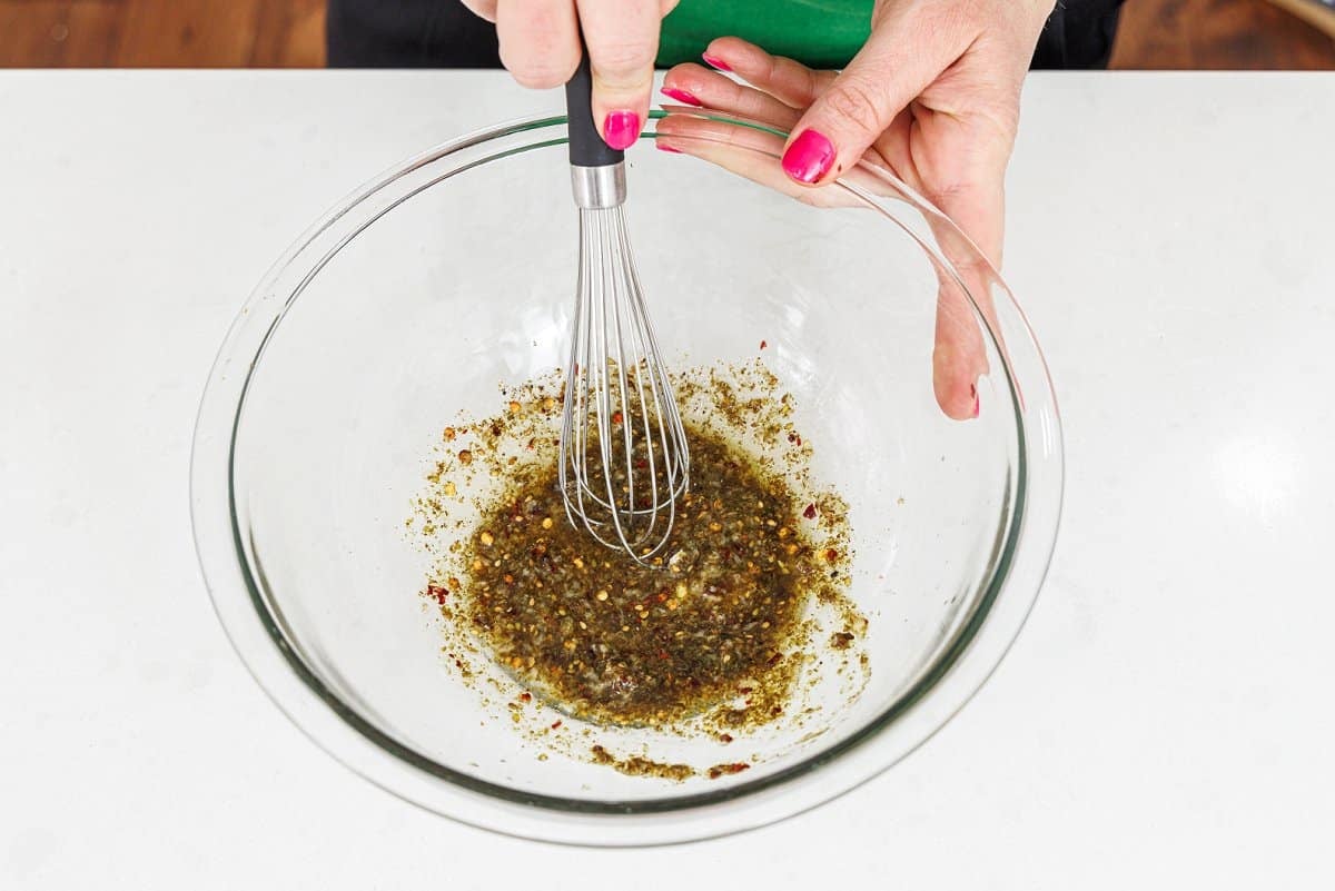 Whisking marinade for shrimp in a large glass bowl.