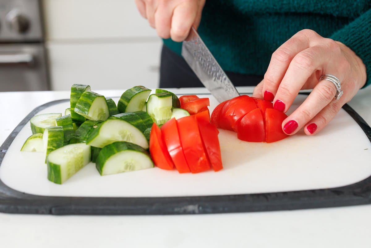 Liz cutting cucumber and tomatoes into small chunks.