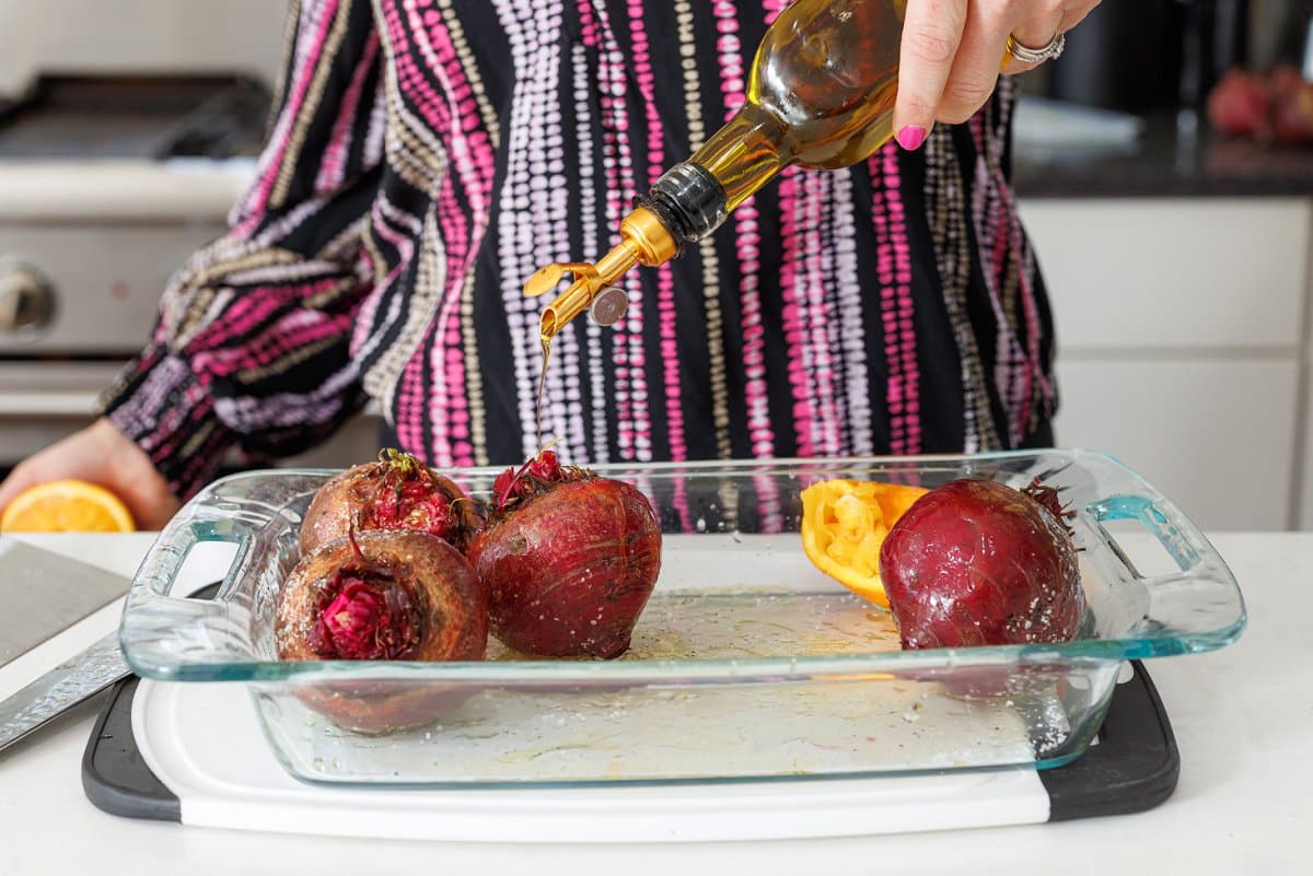 Drizzling olive oil over the top of beets and orange halves.