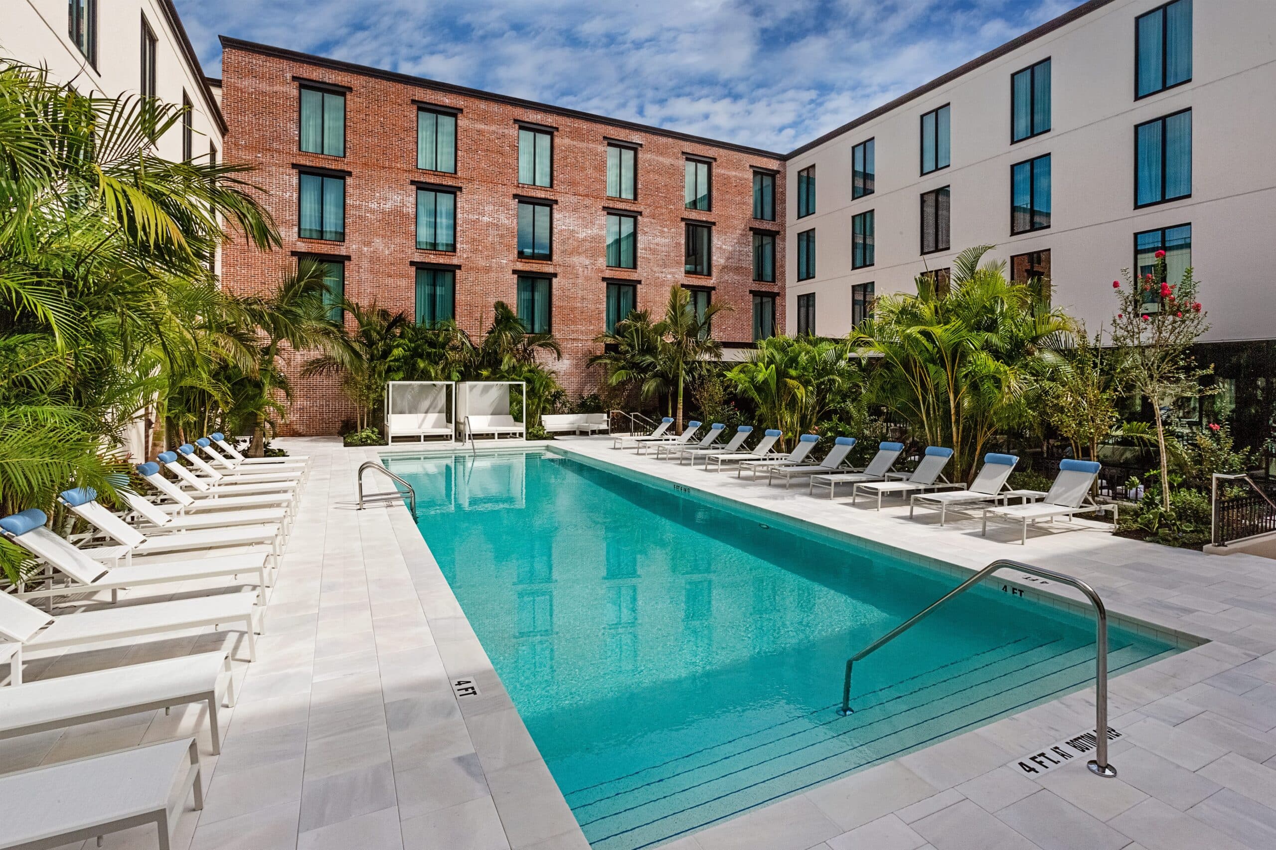 Large empty pool in a courtyard, surrounded by beach chairs.