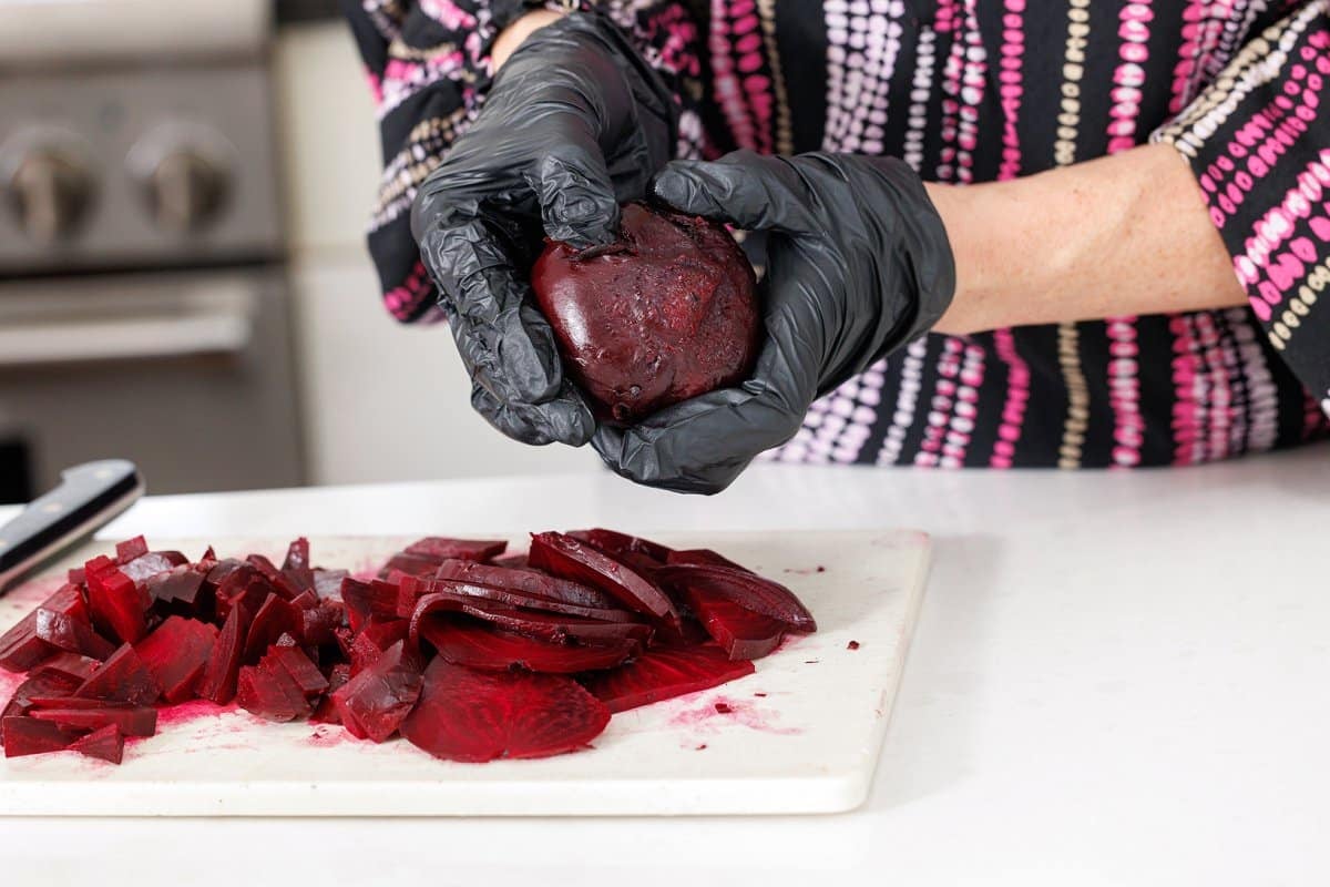 Peeling a roasted beet with black gloves on.