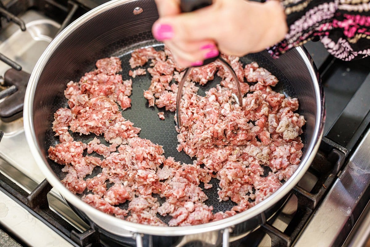 Breaking up Italian sausage in a large skillet.
