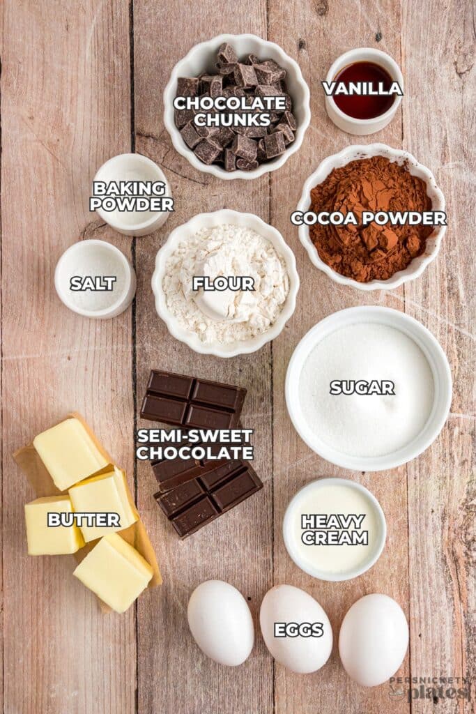Overhead shot of labeled brownie ingredients in bowls on a wooden surface.