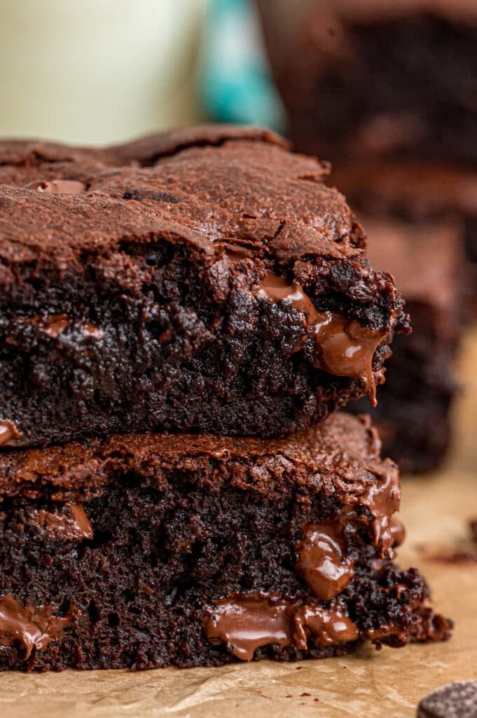 Close-up of gooey chocolate brownies stacked on a wooden surface.