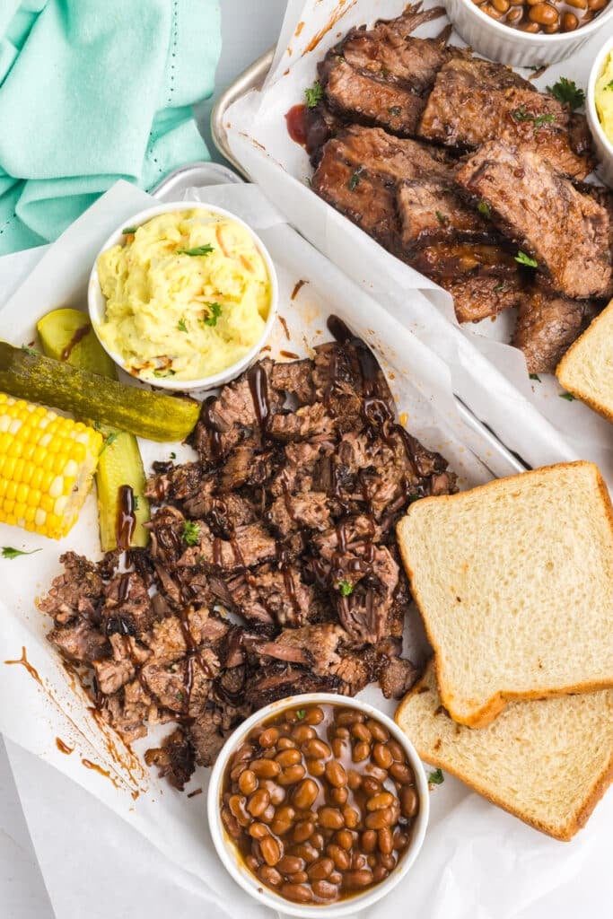 Brisket meal with bread, beans, corn, and potato salad.