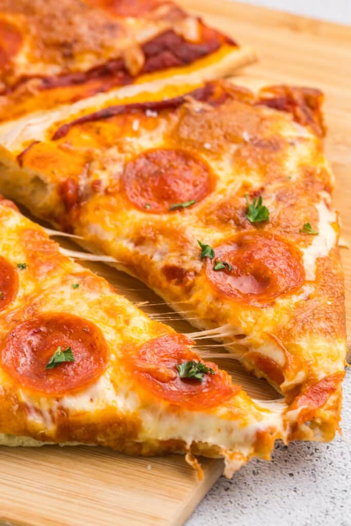 Two slices of pepperoni pizza with melted cheese and small parsley pieces on top.