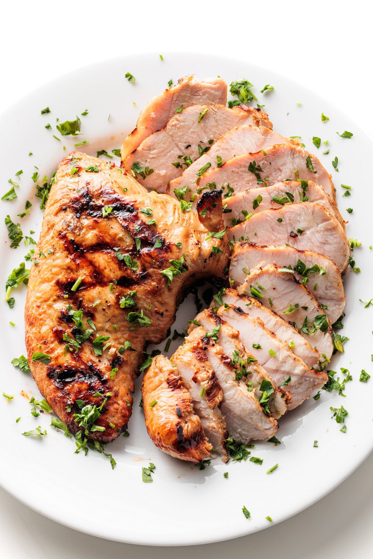 Sliced grilled teriyaki turkey tenderloins on a plate.