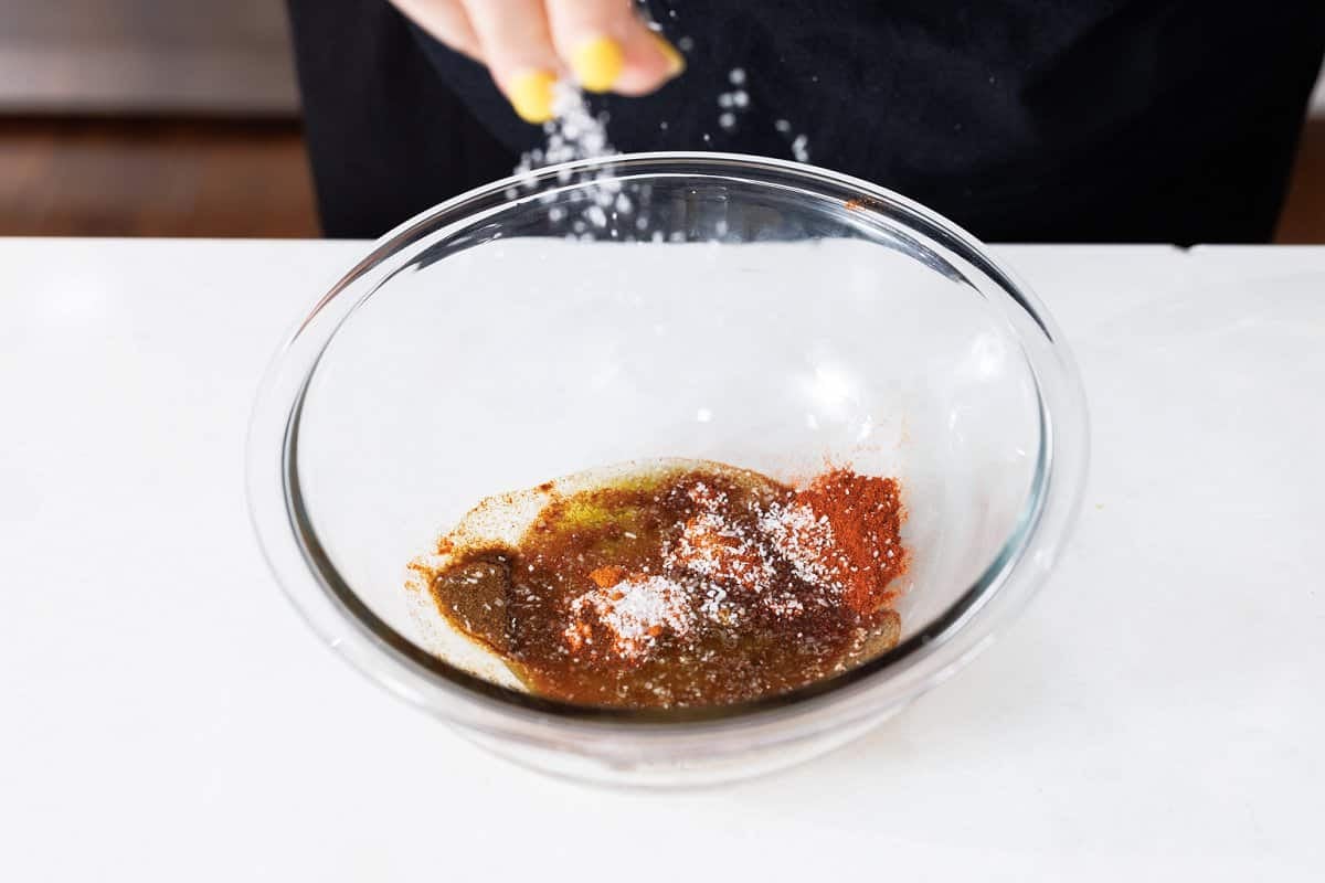 Adding all spices to a bowl for marinade.