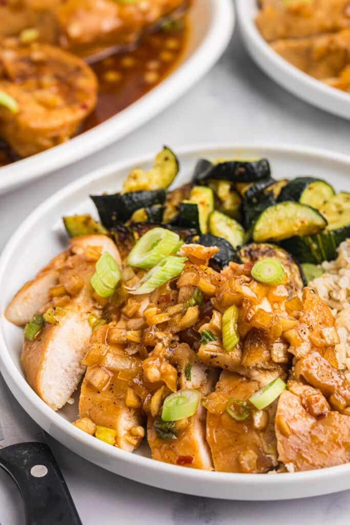 Sliced honey bourbon chicken topped with sauce, served with zucchini and rice.