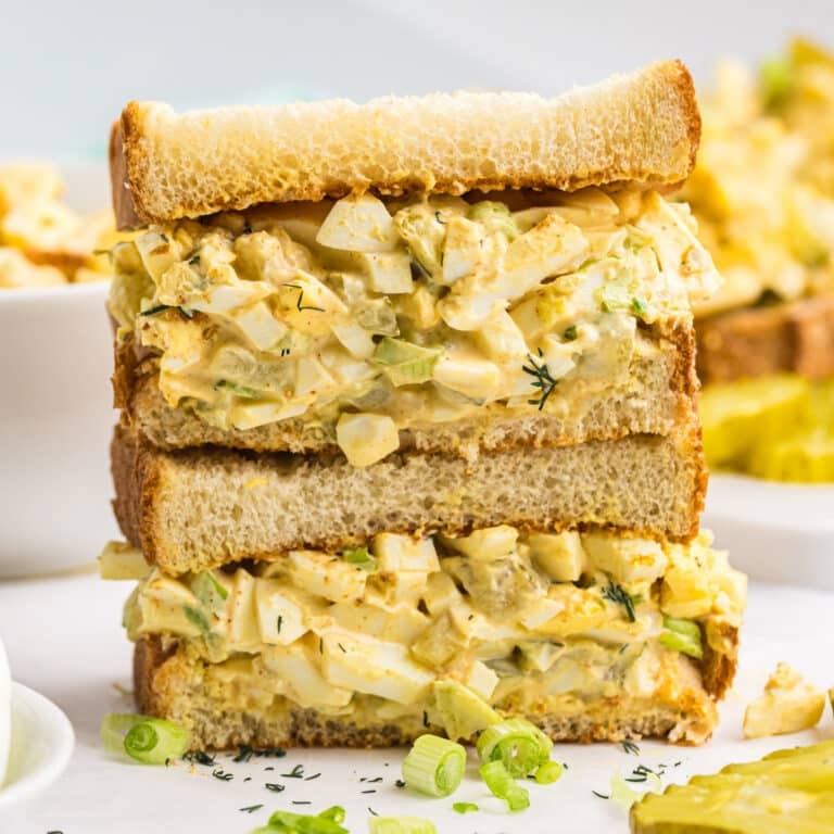 A stacked egg salad sandwich filled with creamy dill pickle egg salad.