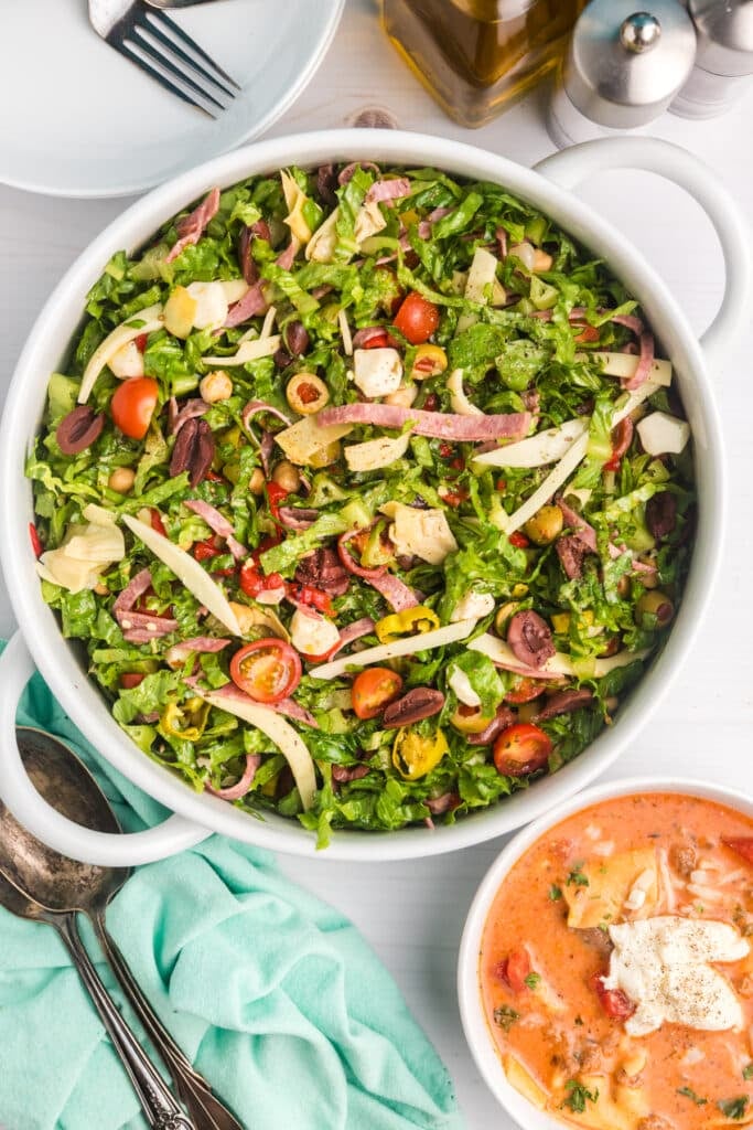 Large bowl of antipasto salad next to a bowl of lasagna soup.