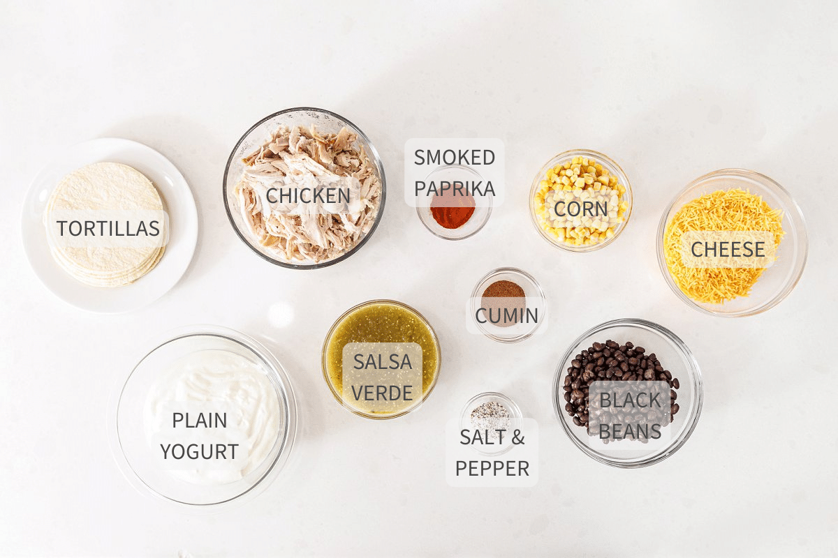 Labeled ingredients for Mexican lasagna with chicken and beans against a white counter top.