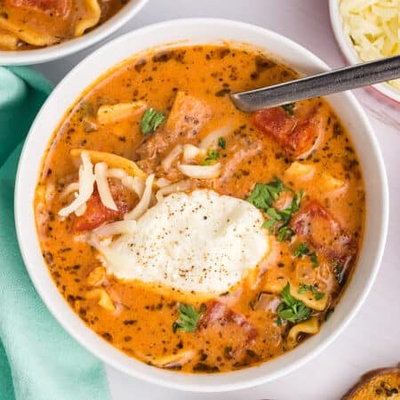 Lasagna soup in a white bowl with cheese topping.