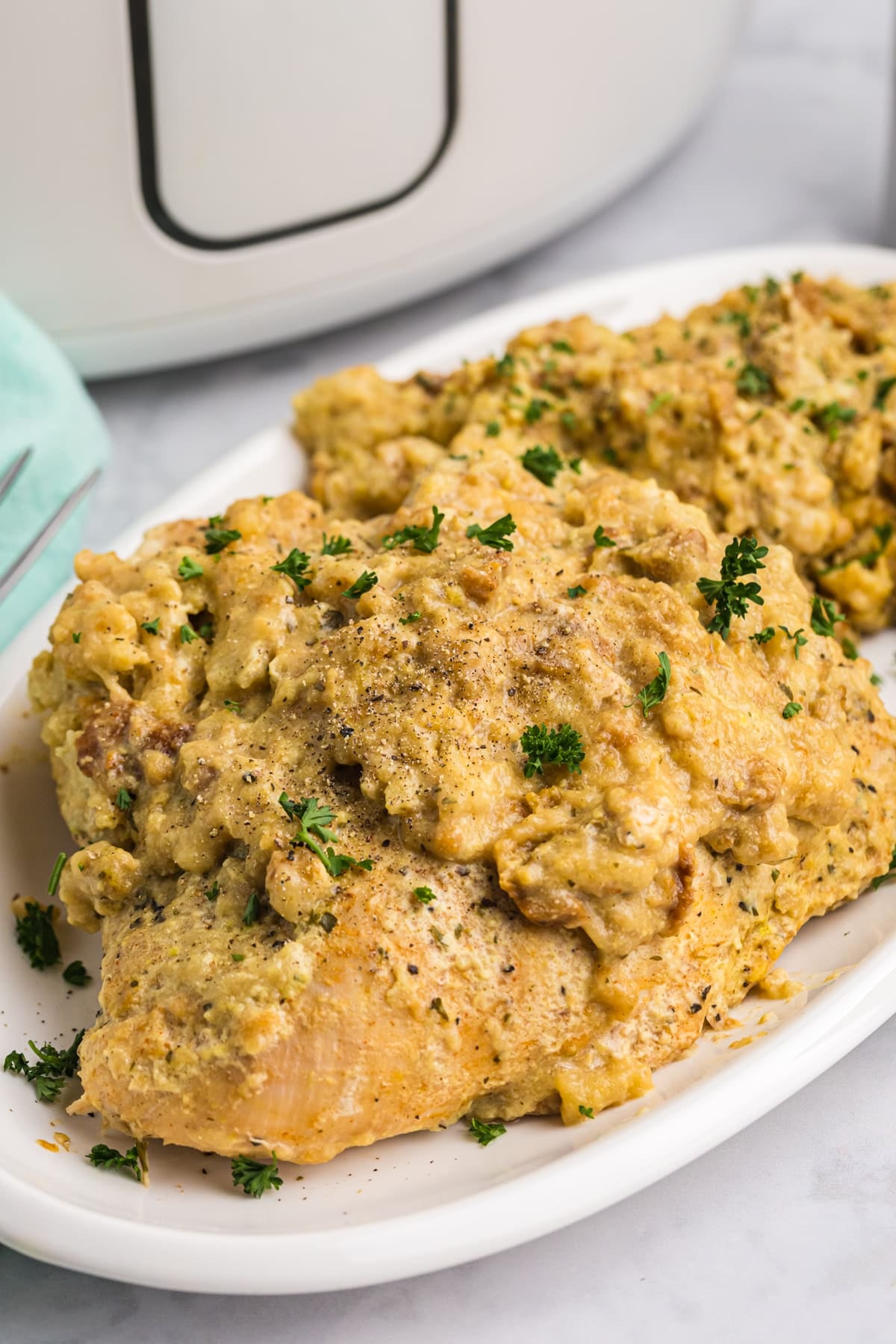 Cooked turkey breasts topped with stuffing on a white platter.