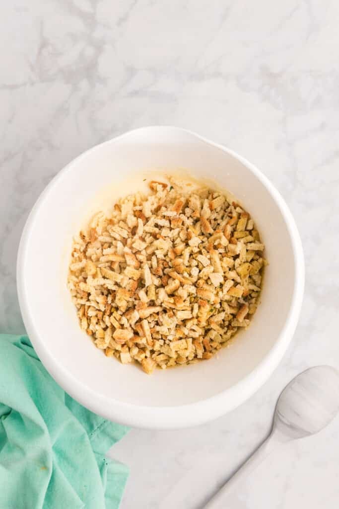 Stuffing mix in a white bowl on a marble counter.