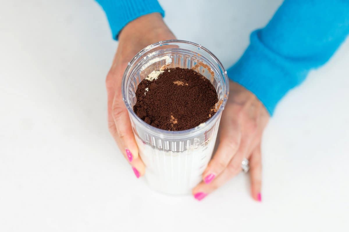 Milk in a glass with cocoa powder and espresso powder floating on top.