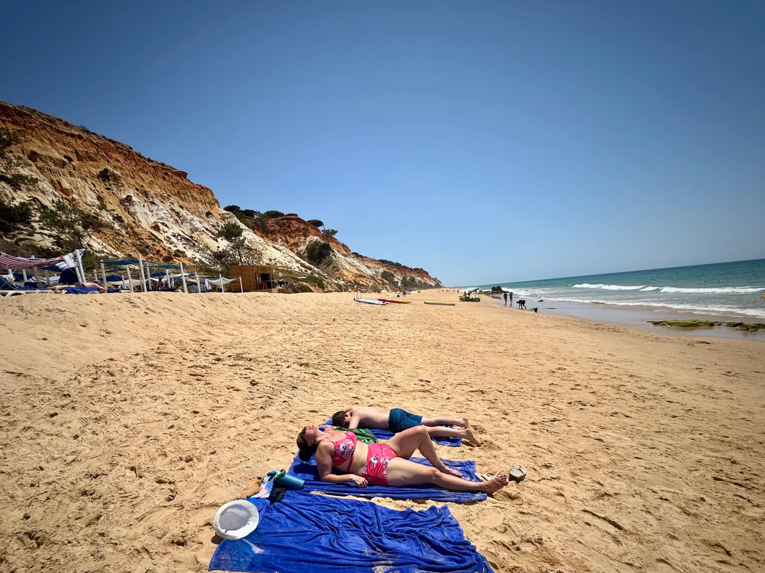 Liz and son laying on towels at the beach in Portugal.