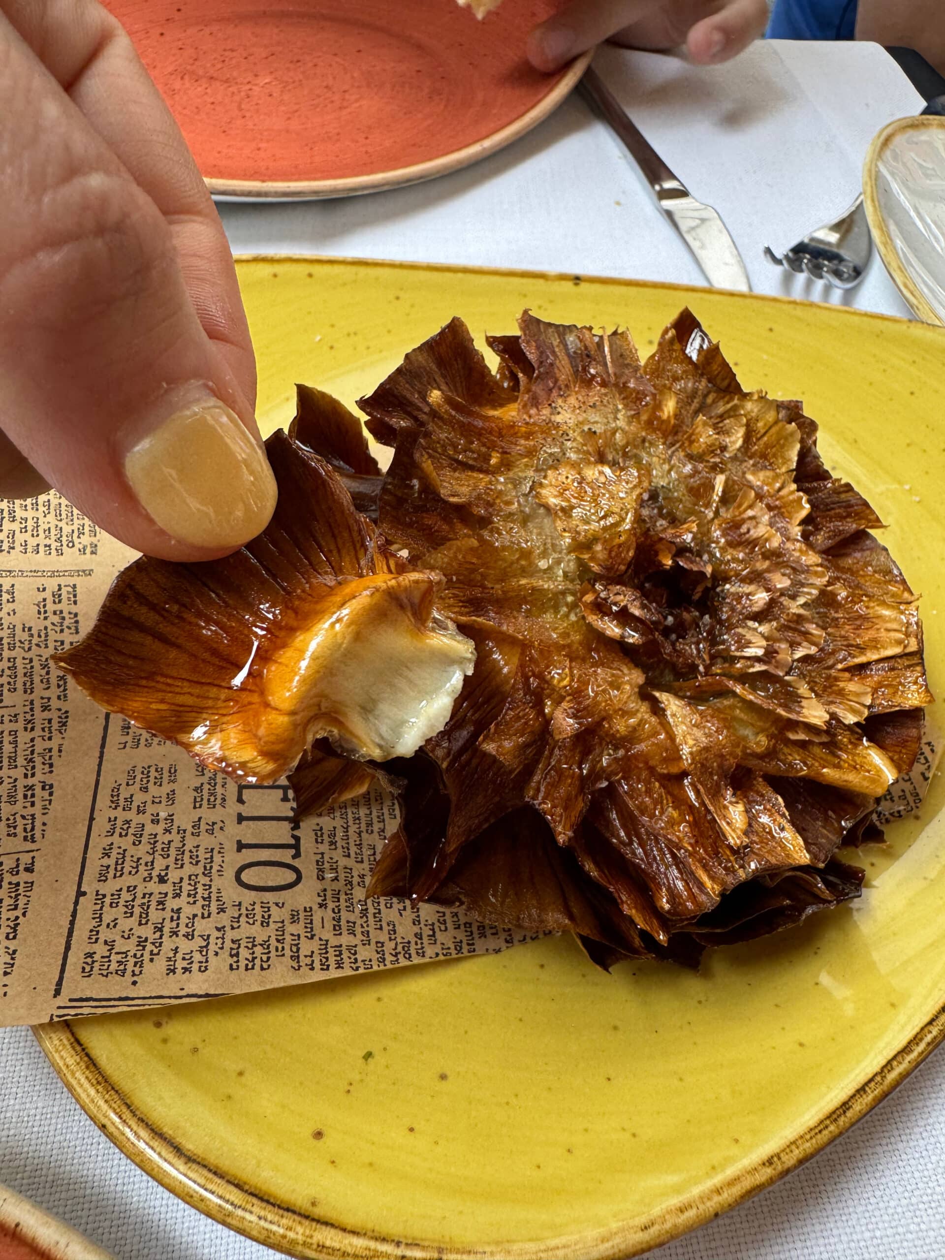Peeling a leaf off of a Jewish artichoke.