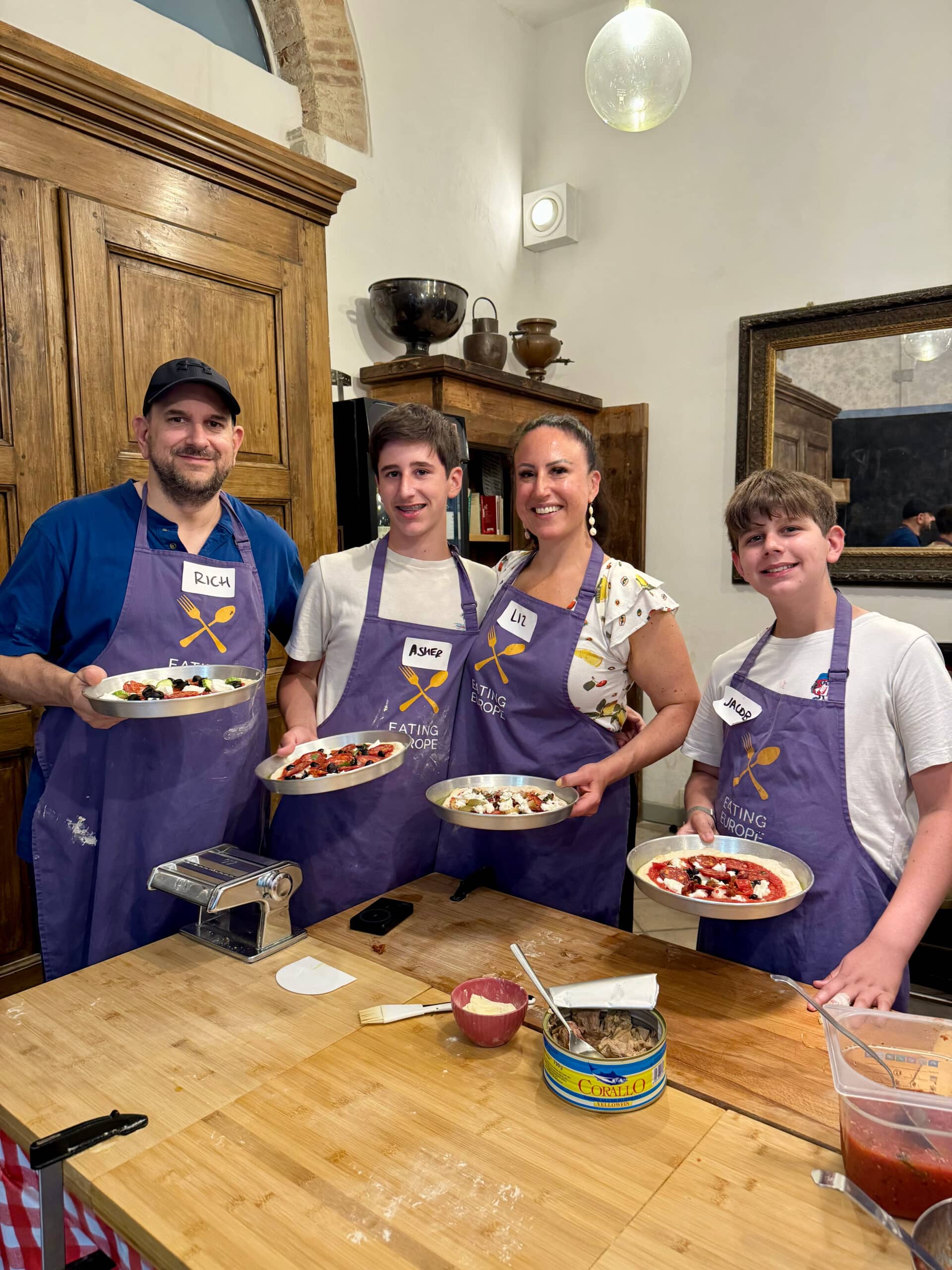 Liz and family holding homemade pizzas from a cooking class in Florence.
