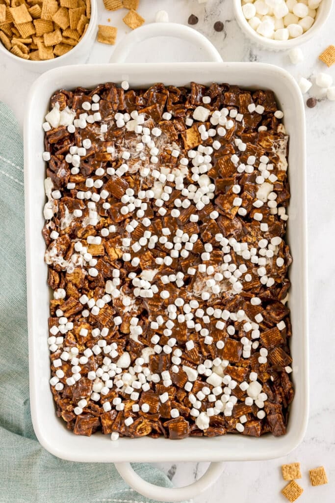 Pan of Golden Grahams s’mores bars topped with marshmallows, surrounded by bowls of ingredients.