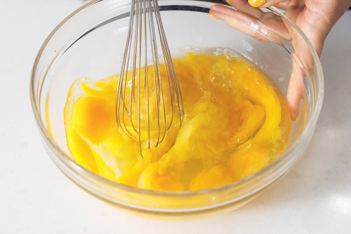 Whisking eggs in a large glass bowl.