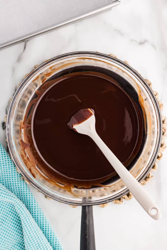 Bowl of smooth melted chocolate with spatula resting inside.