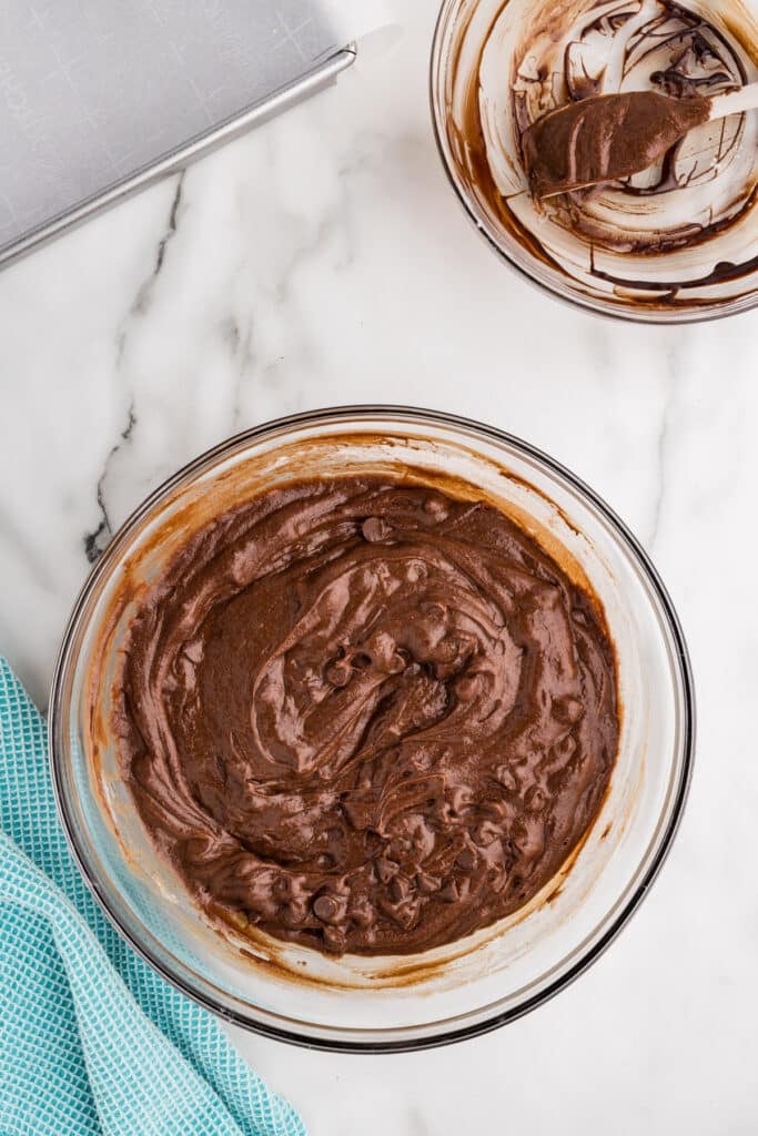 Glass mixing bowl filled with thick chocolate brownie batter.