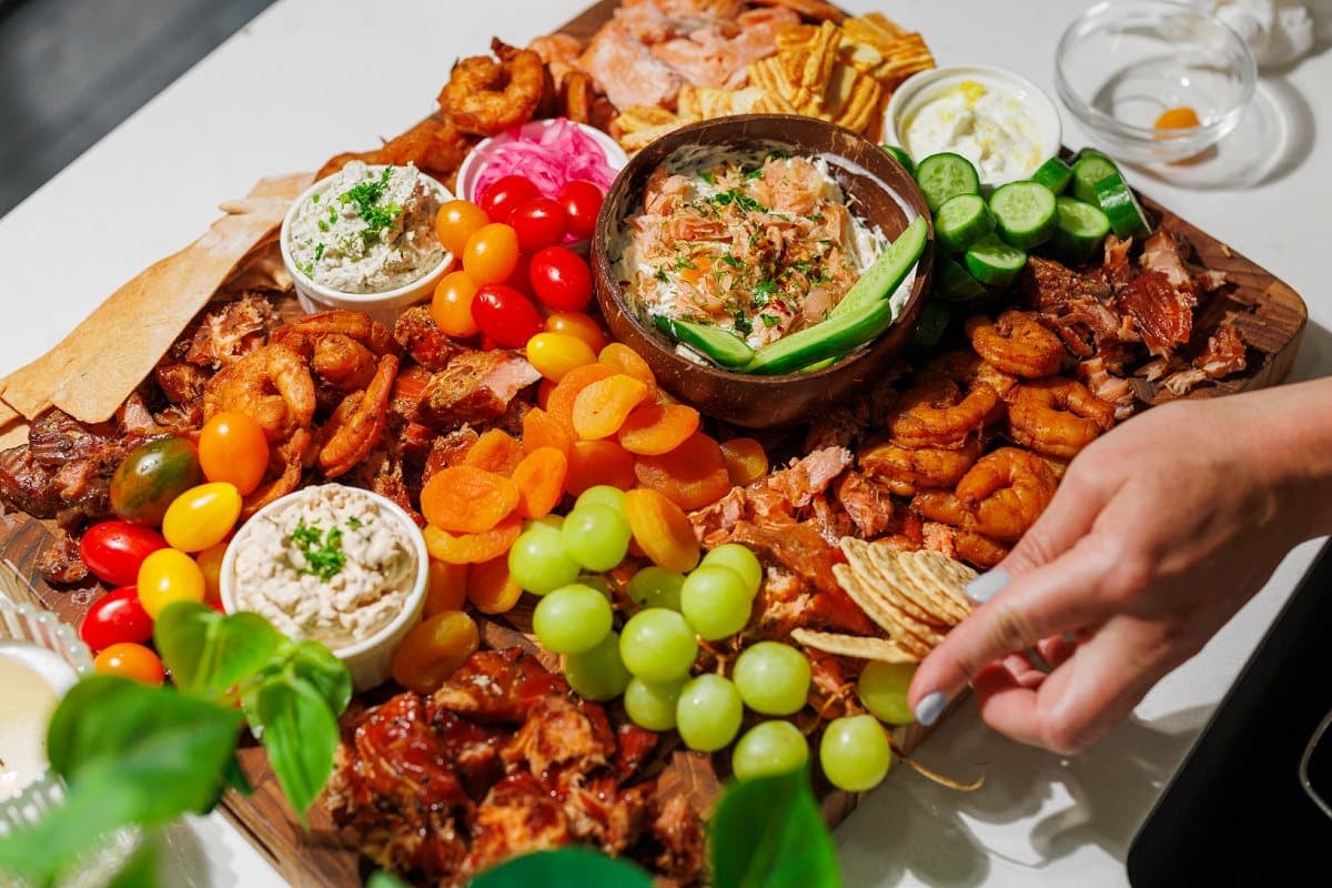 Adding crackers to a smoked fish charcuterie board.