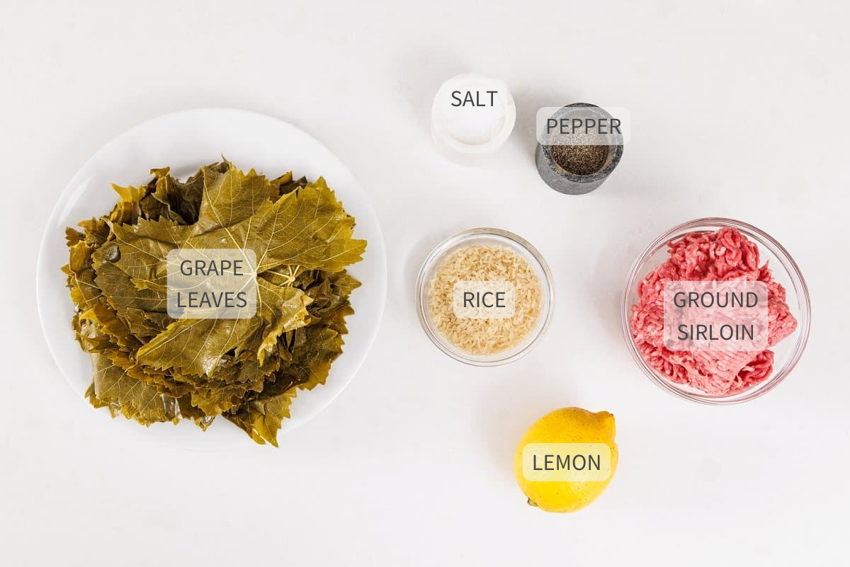 Labeled ingredients for Lebanese meat stuffed grape leaves on a white counter.
