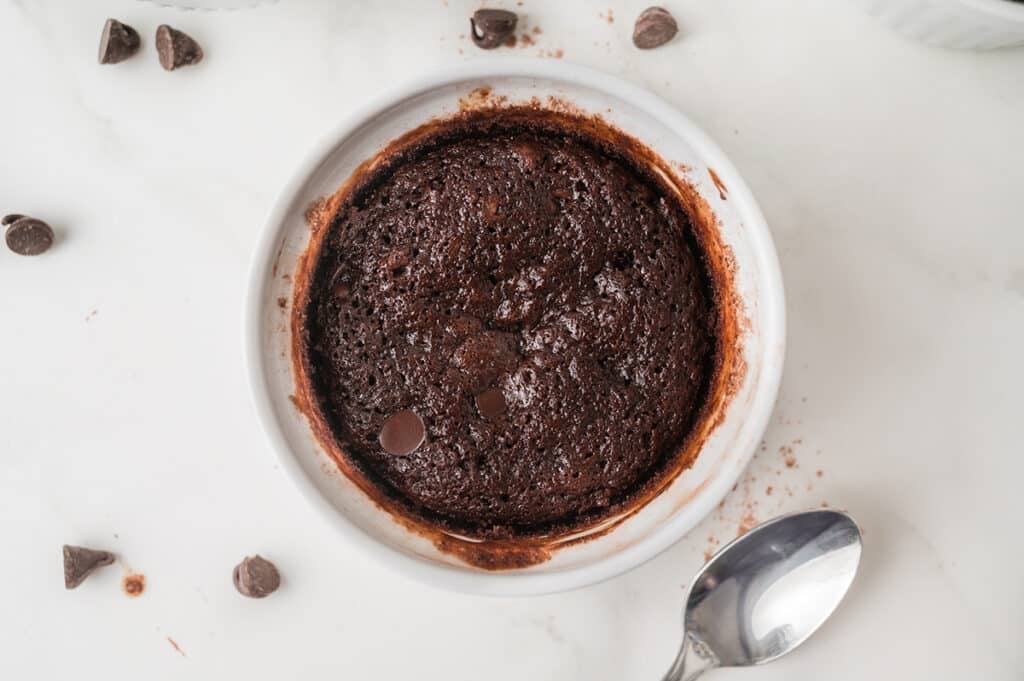 Freshly baked single serve brownie in a white ramekin with chocolate chips.