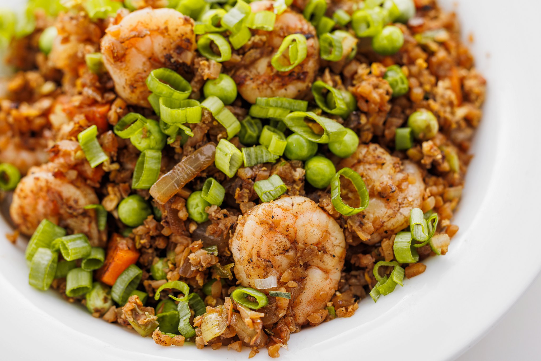 Shrimp fried cauliflower rice on a white plate.