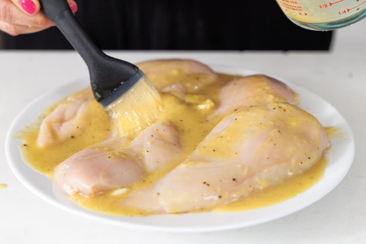 Brushing chicken breasts with maple dijon marinade.