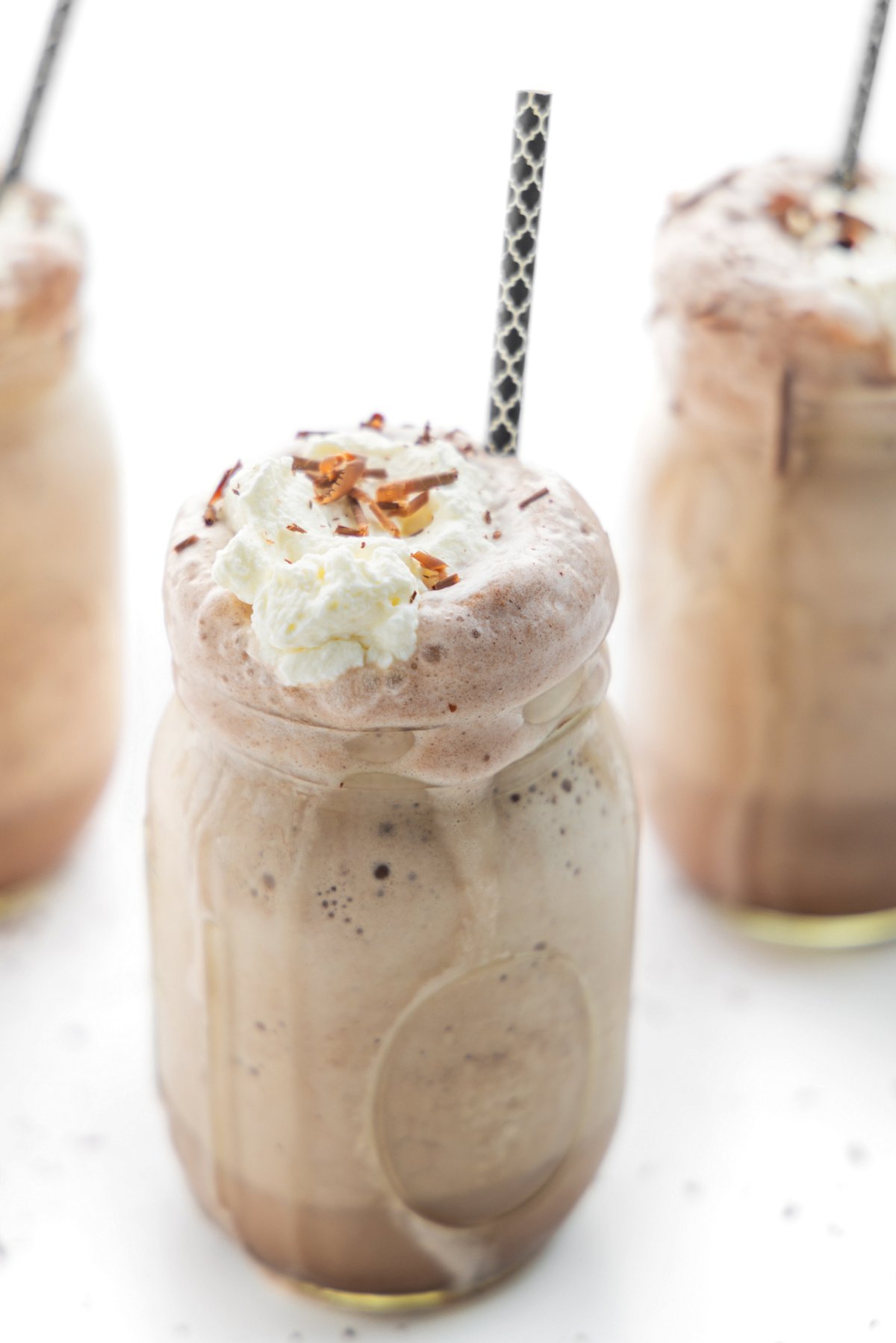 Mason jar mug filled with frozen hot chocolate with a straw.