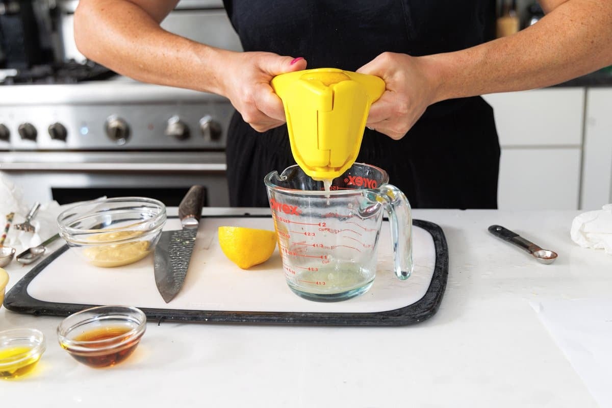 Using a juicer to juice lemon into liquid measuring cup.