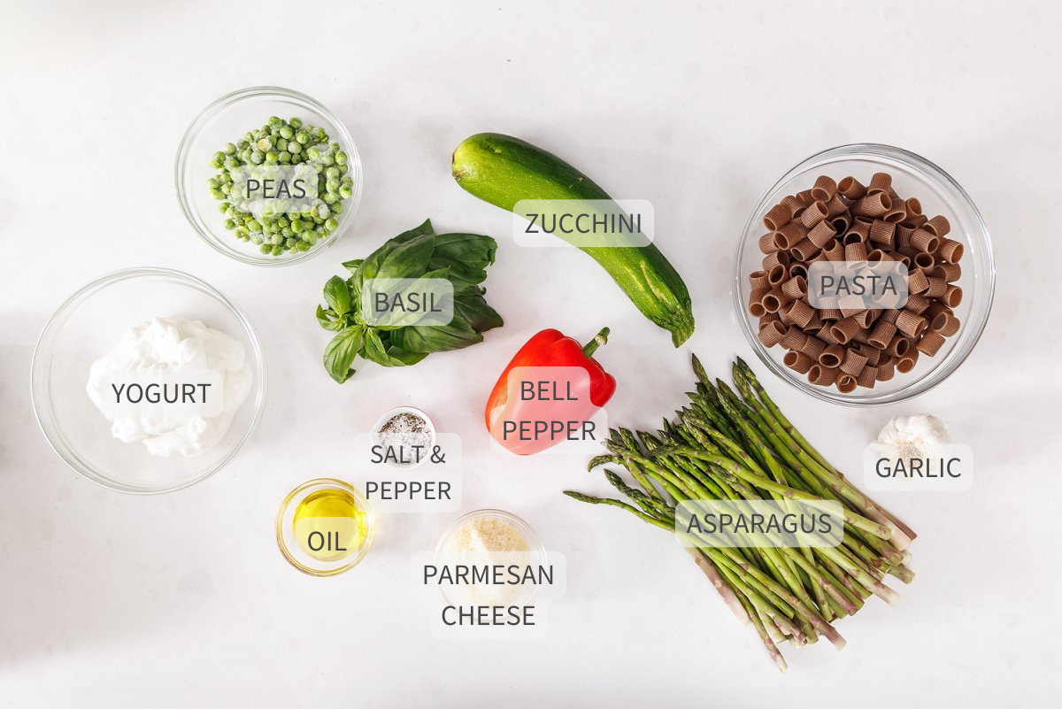 Labeled ingredients for primavera pasta with sautéed vegetables on a white counter.