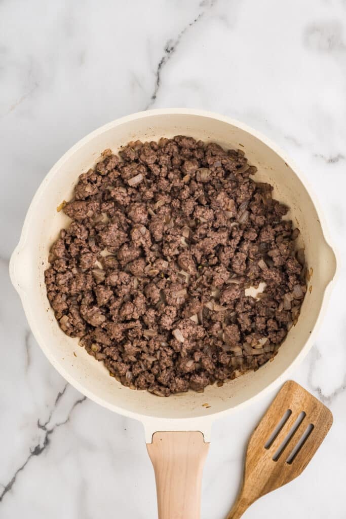 Ground beef and onions cooking in a skillet.