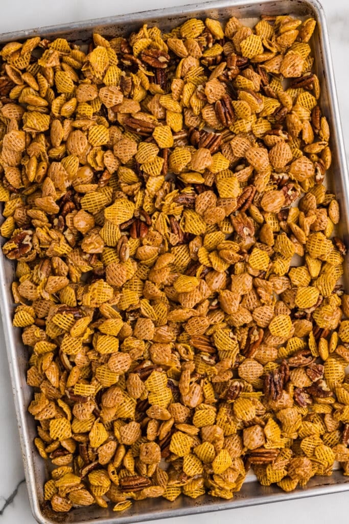 Butter pecan snack mix spread out on a baking sheet.