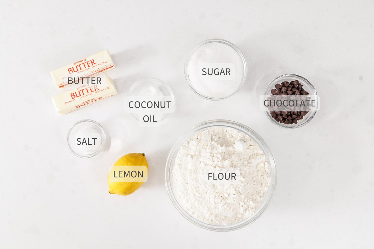 Labeled ingredients for lemon shortbread cookies with chocolate drizzle on a white counter.