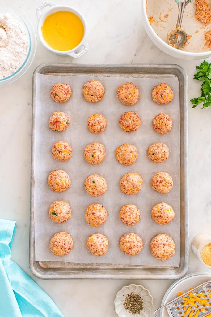 Unbaked sausage balls arranged on a parchment-lined baking sheet.