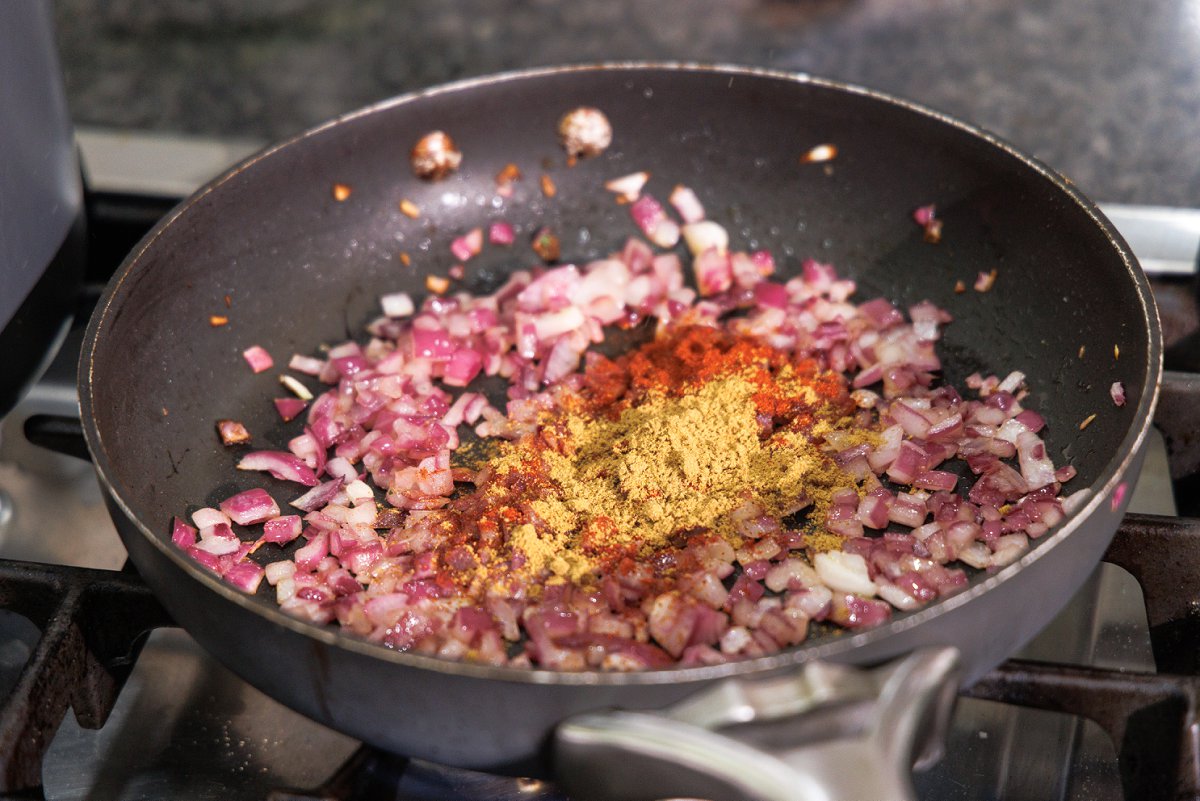 Cooked red onion in a skillet with cumin and smoked paprika.