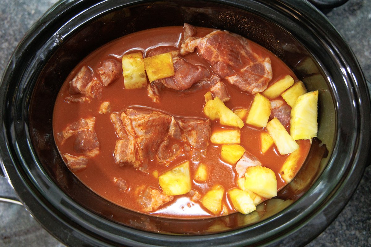 Pork and pineapple in slow cooker covered in al pastor sauce.
