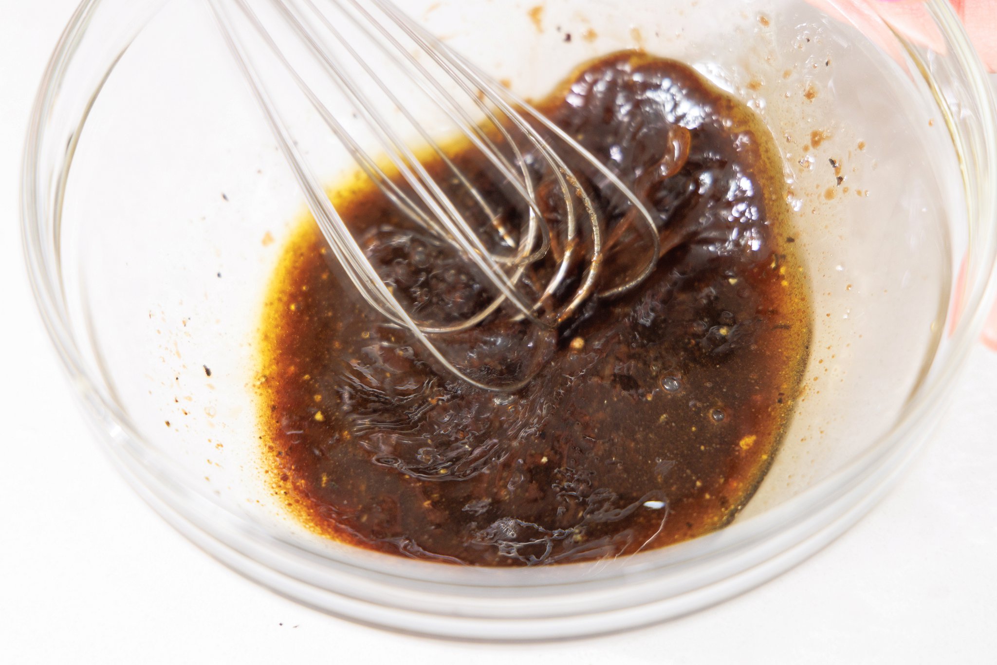 Whisking balsamic vinaigrette in a glass bowl.