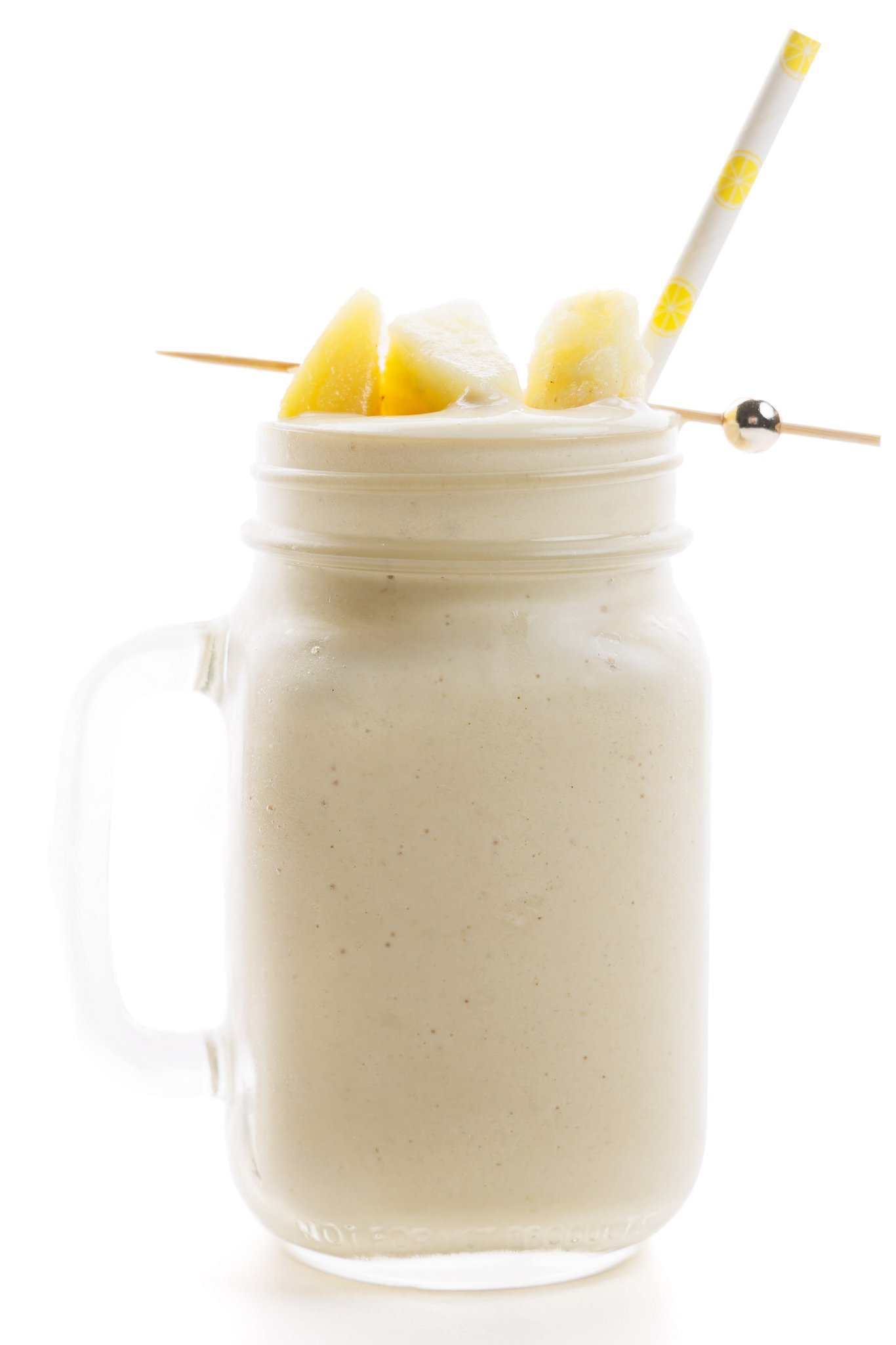 Striped straw sticking out of pina colada protein smoothie in a mason jar glass.