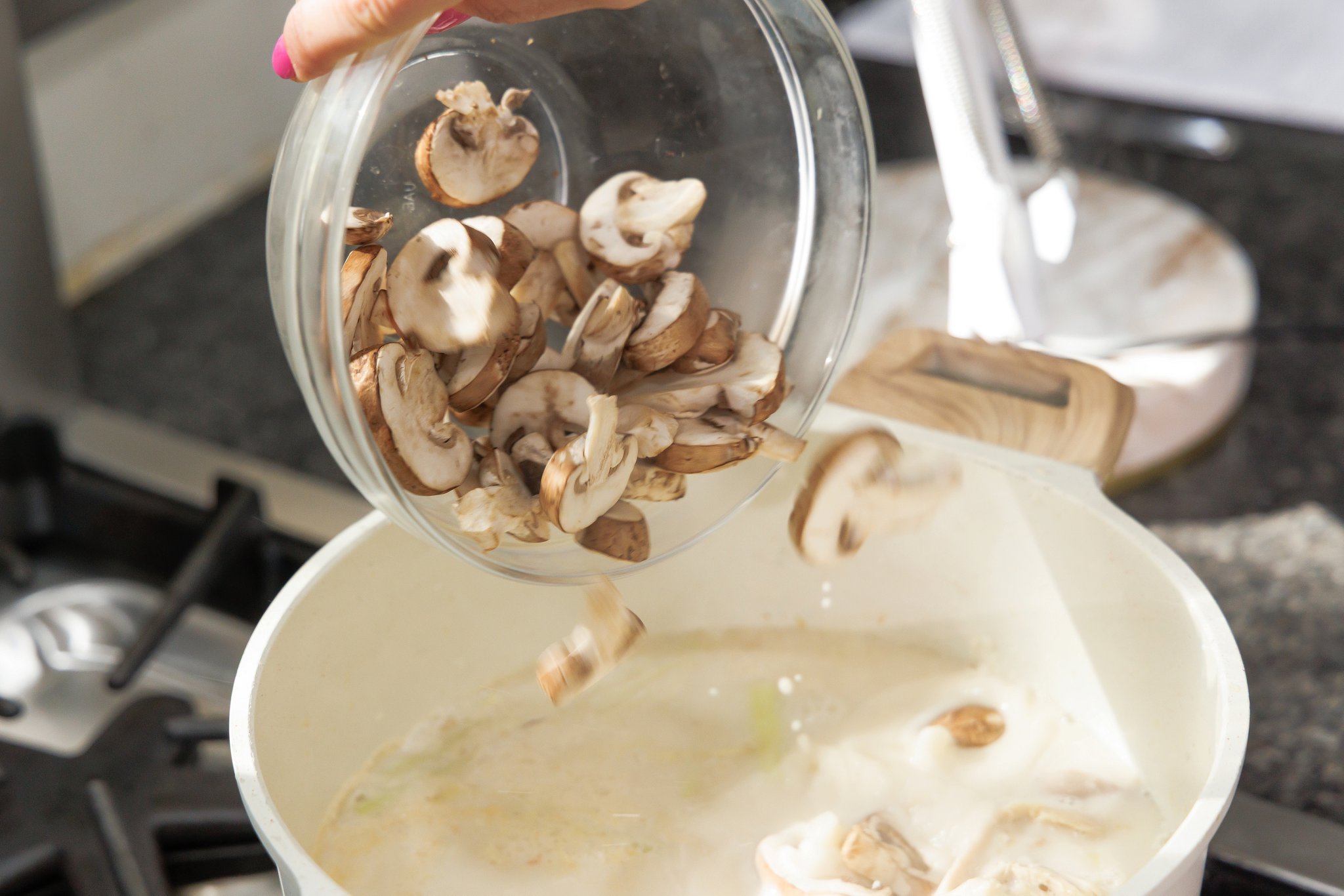Adding sliced mushrooms to soup.