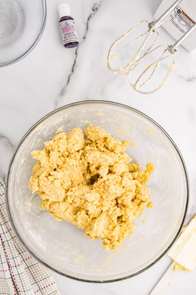 Plain cookie dough in a glass bowl on a marble counter.