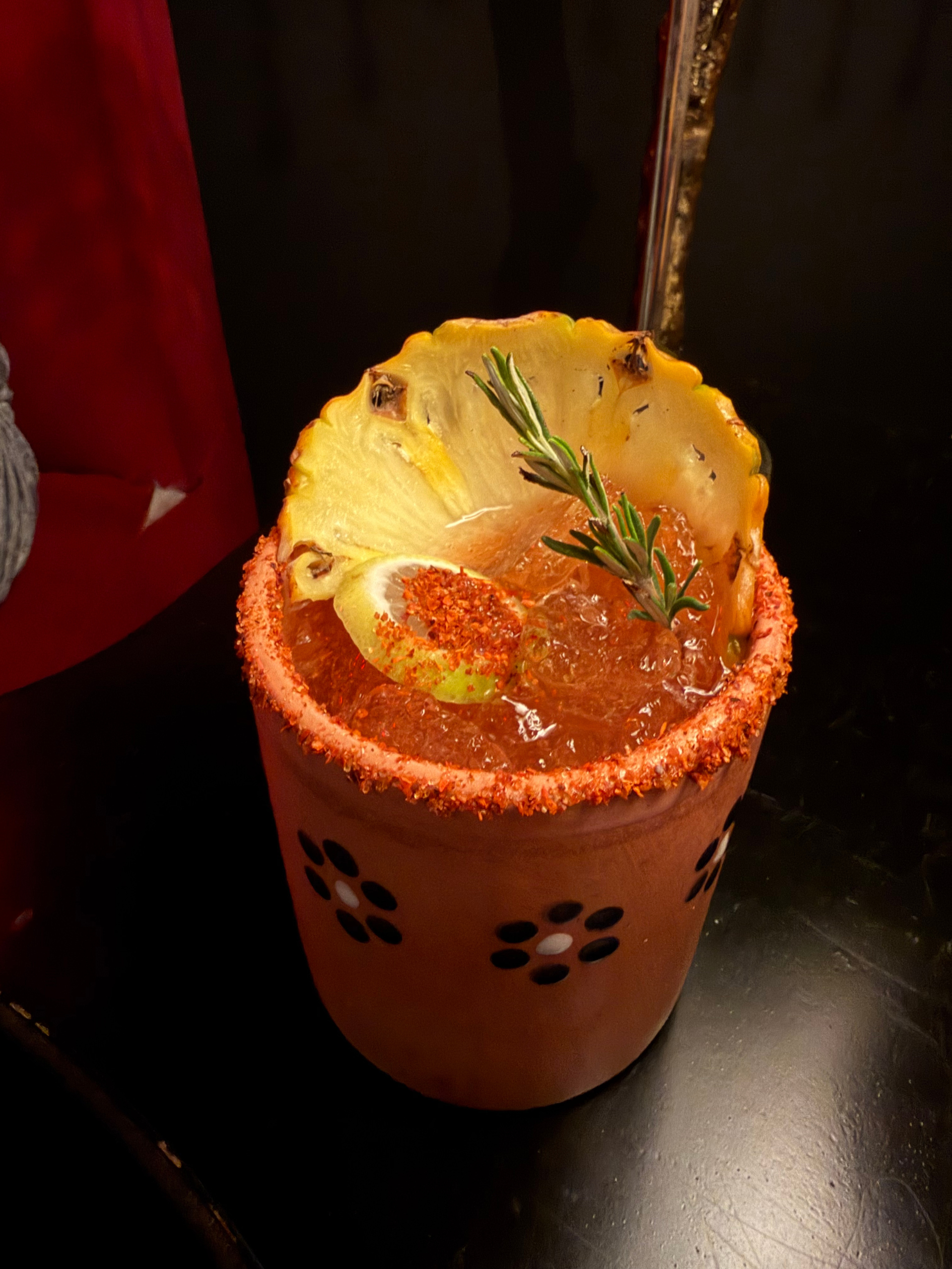 A spicy pineapple margarita in a ceramic cup with a salted rim.