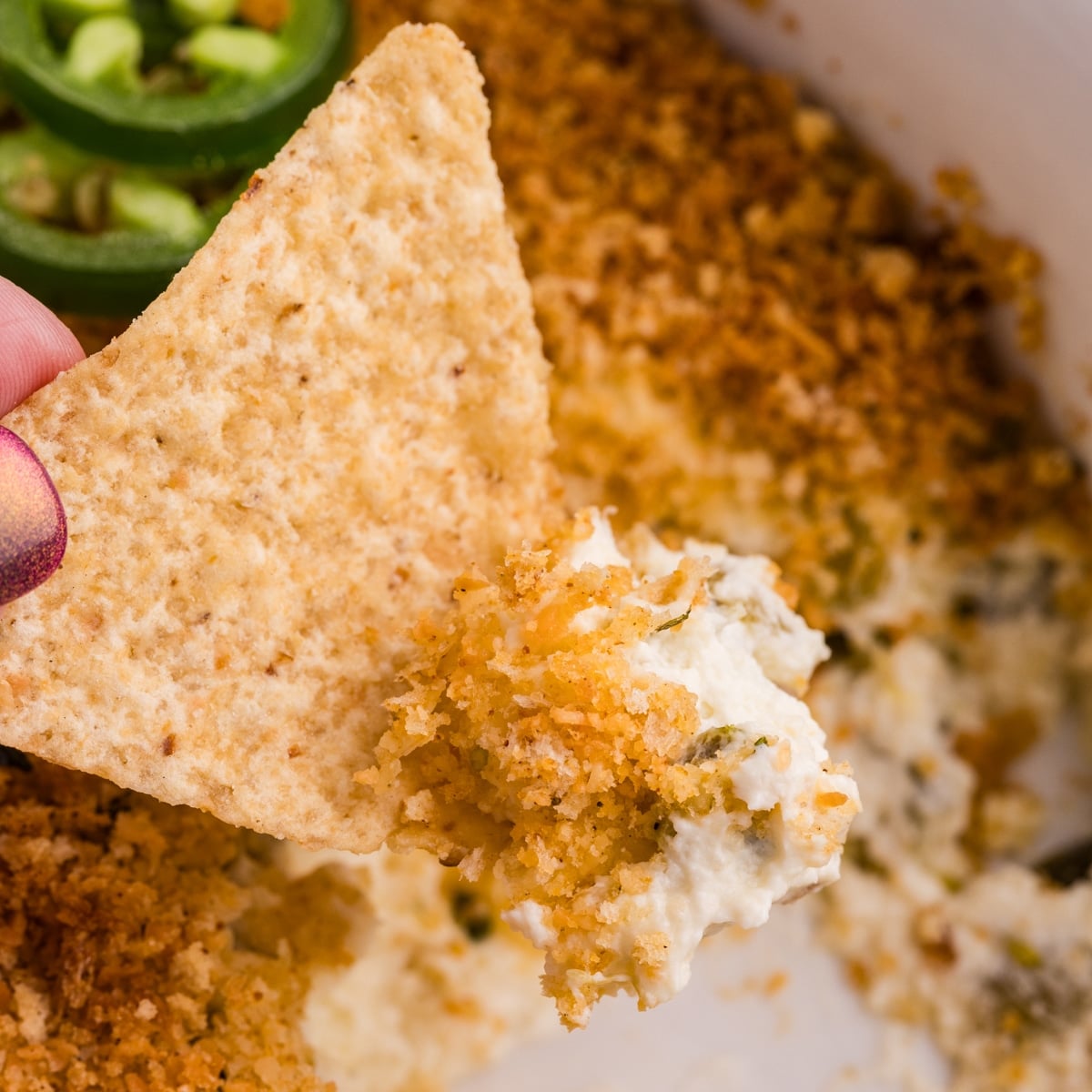 Tortilla chip dipped into jalapeรฑo popper dip.