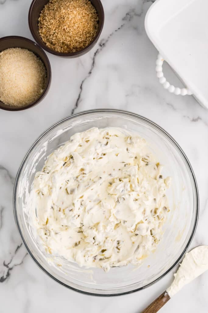 Creamy jalapeño dip mixture in a glass mixing bowl.